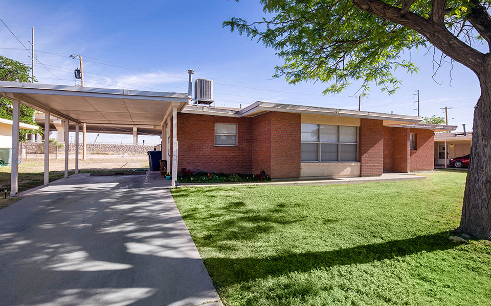 the front of a brick building with a sidewalk and grass