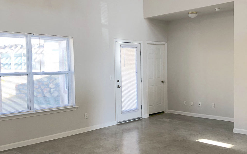 an empty living room with a door and a window
