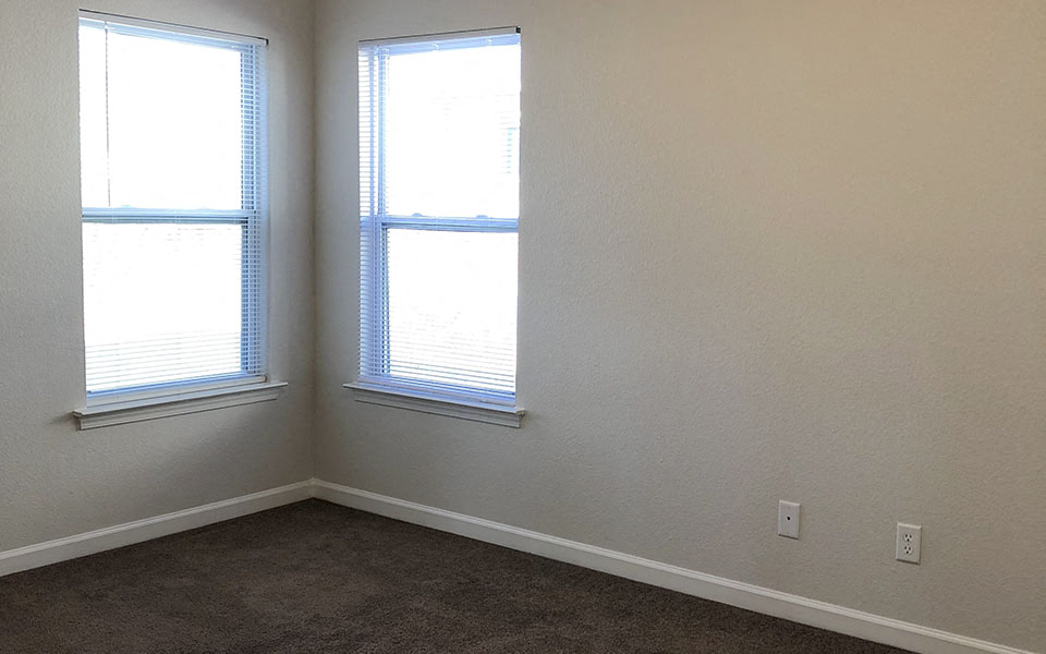 two windows in an empty room with a carpet