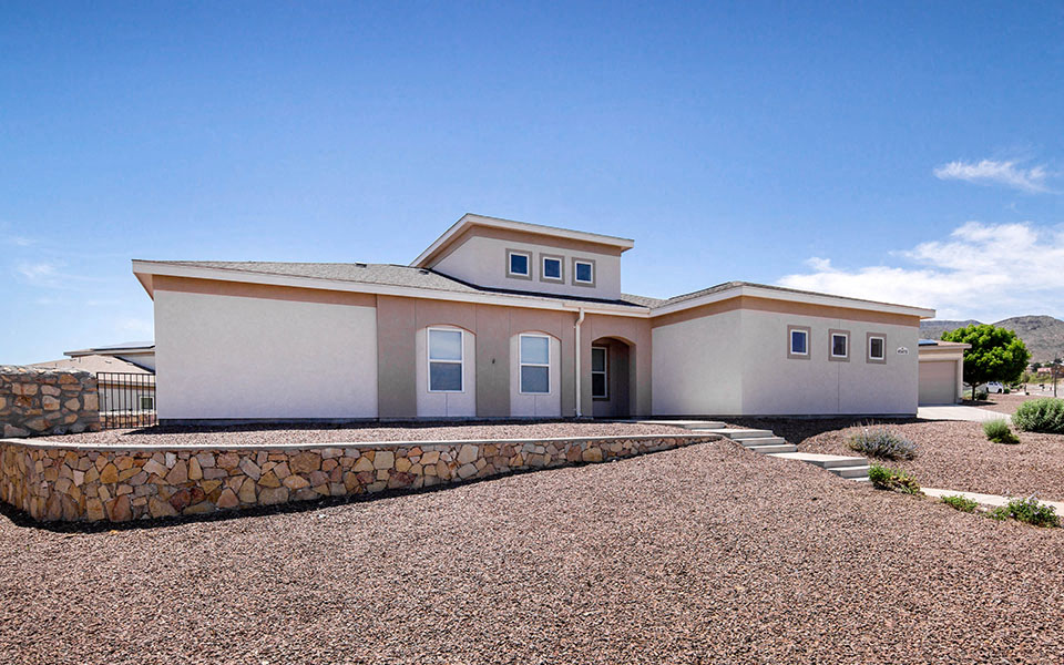 a house with a gravel driveway and a stone wall