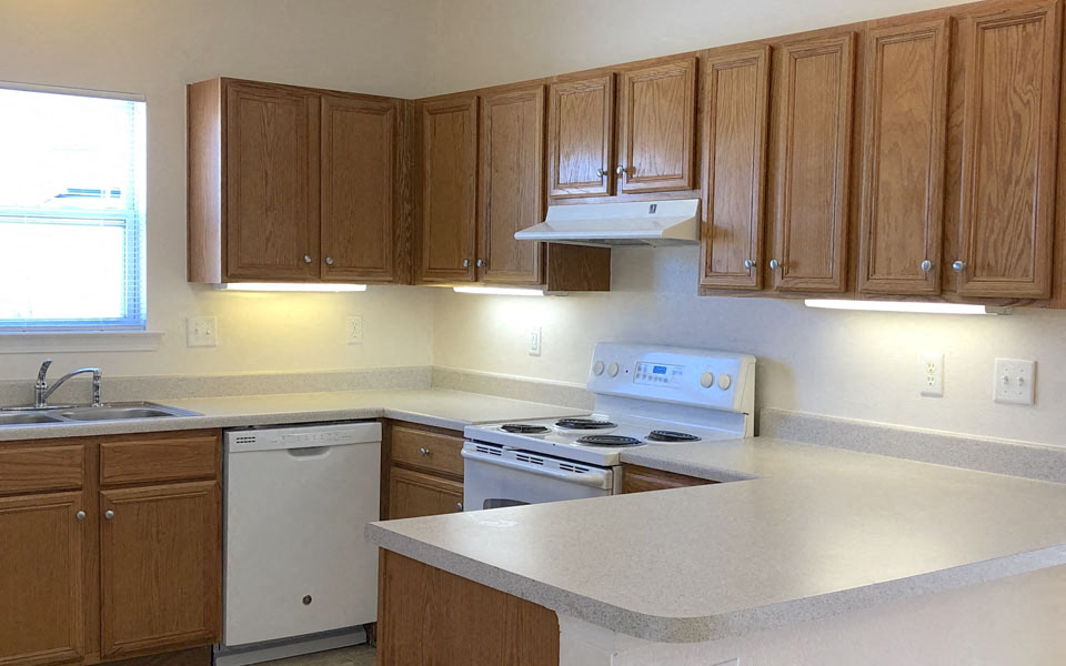 an empty kitchen with wooden cabinets and a white counter top