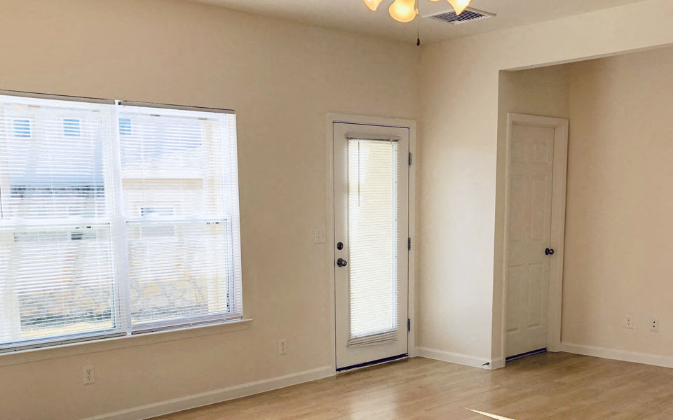 an empty living room with a door and a window