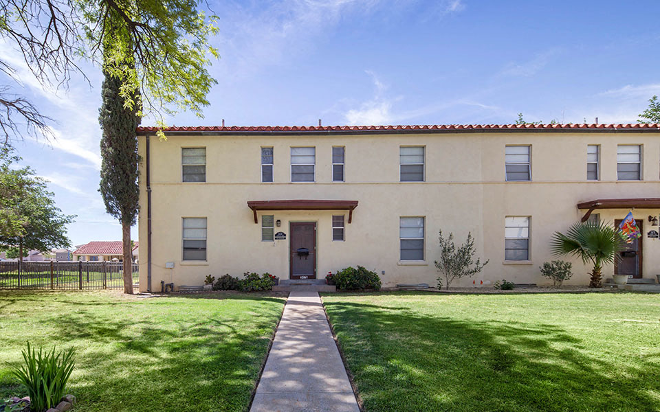 the front of a building with a lawn and a sidewalk