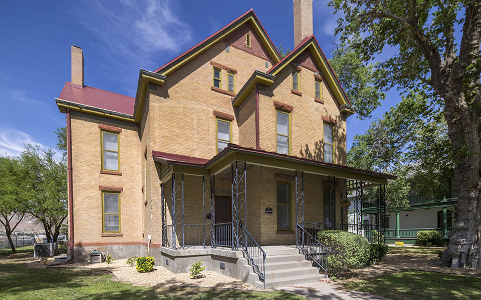 the front of a brick house with trees and a blue sky