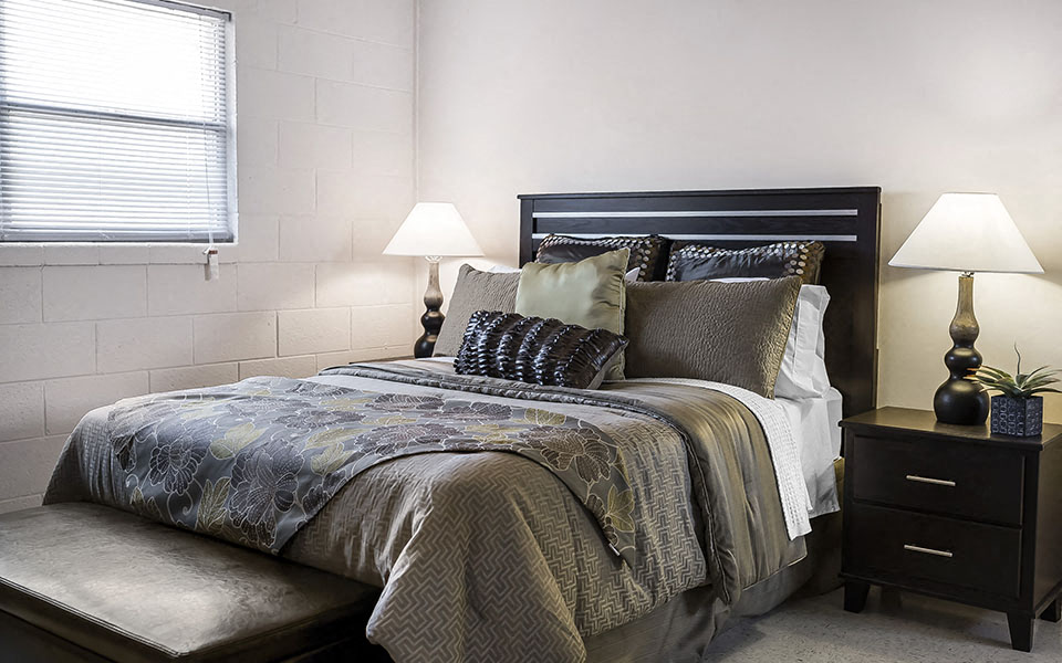 a bedroom with a bed and two lamps and a window