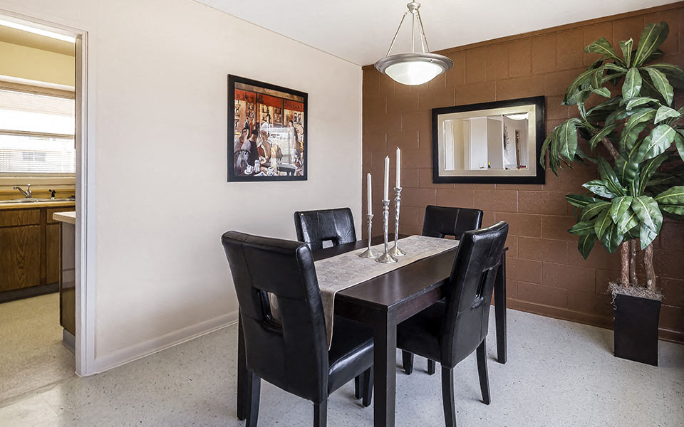 a dining room with a table and chairs and a potted plant