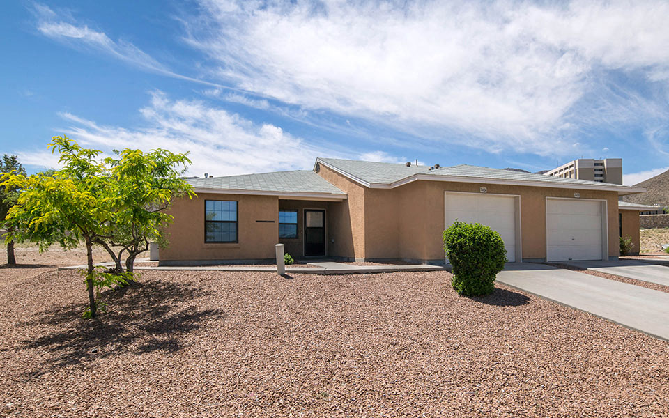a house with two garage doors and a gravel driveway