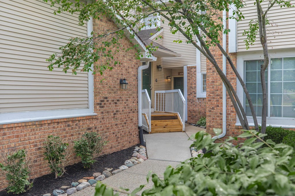 the front of a brick house with a porch and stairs