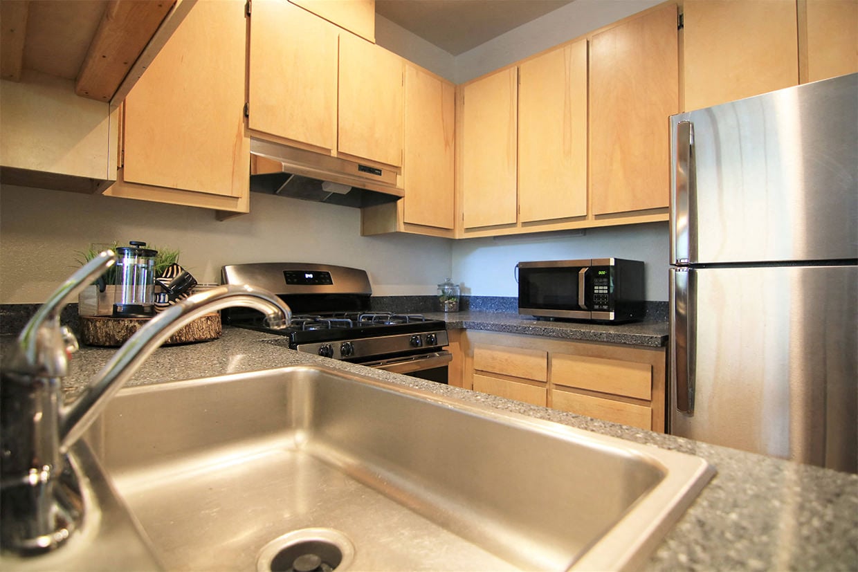 A kitchen with a stainless steel refrigerator and a stainless steel sink.