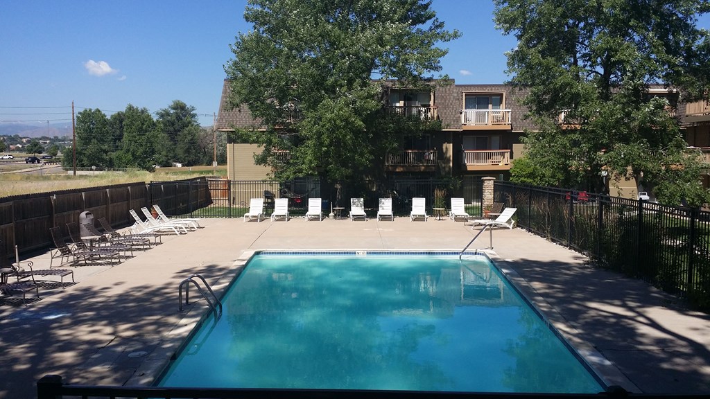 a swimming pool with chairs in front of a house