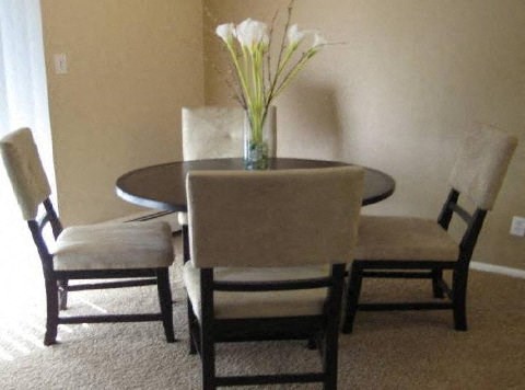 a dining room table with chairs and a vase with flowers