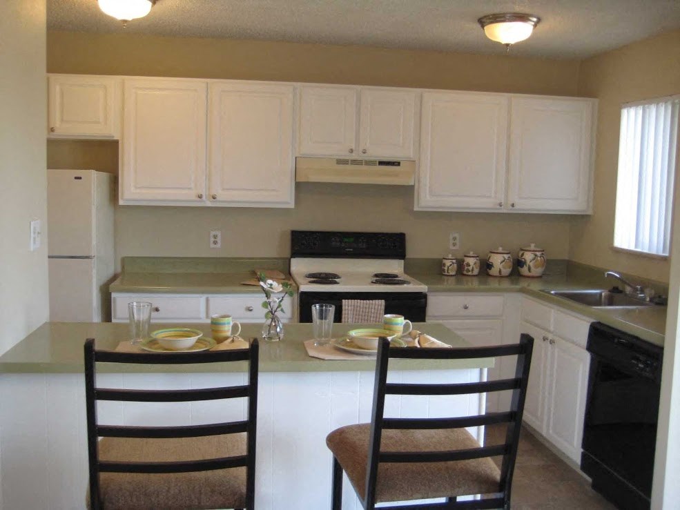 a kitchen with white cabinets and a table with two chairs