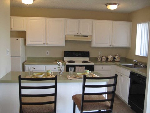 a kitchen with white cabinets and a table with two chairs