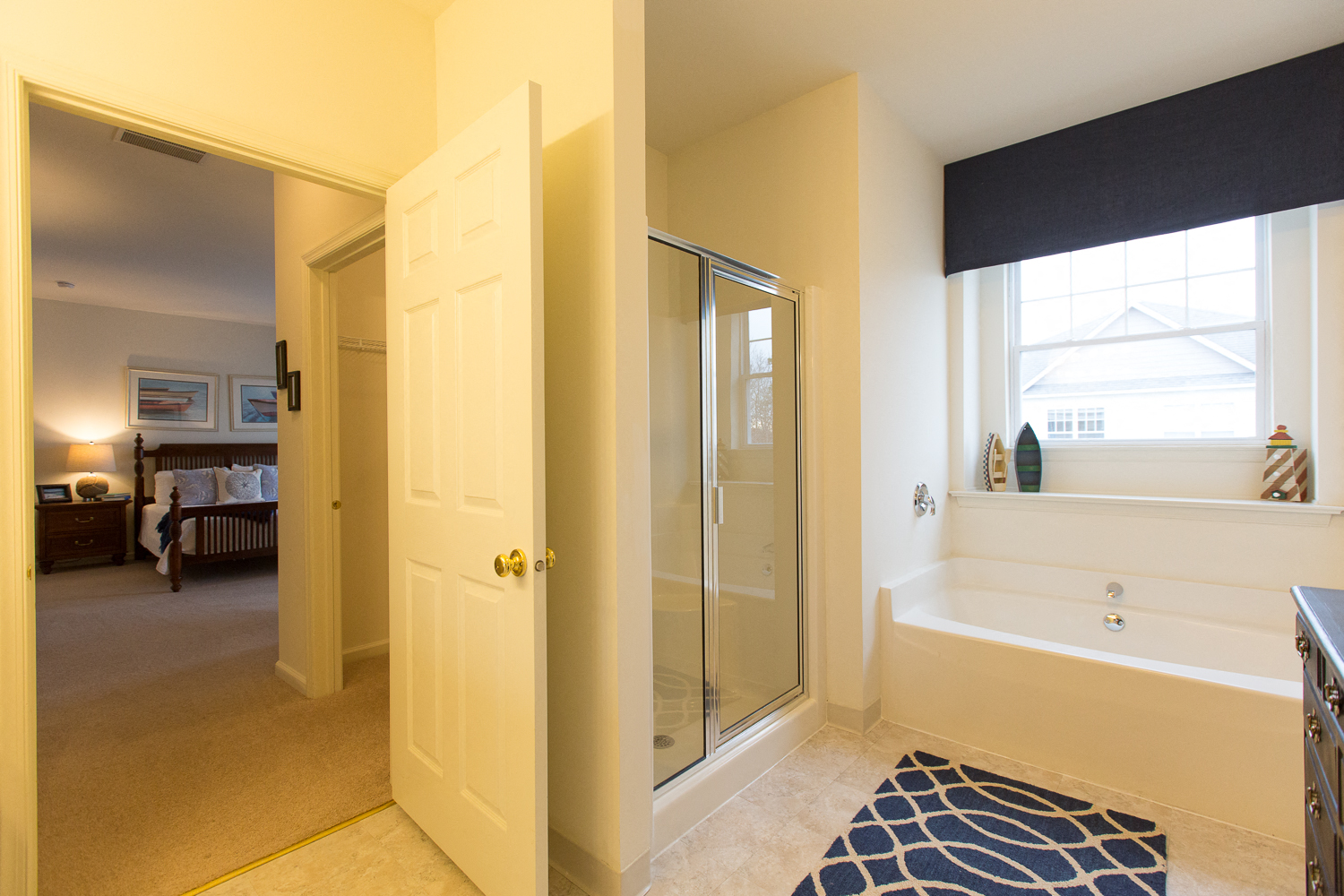a bathroom with a shower and a tub and a door to a bedroom