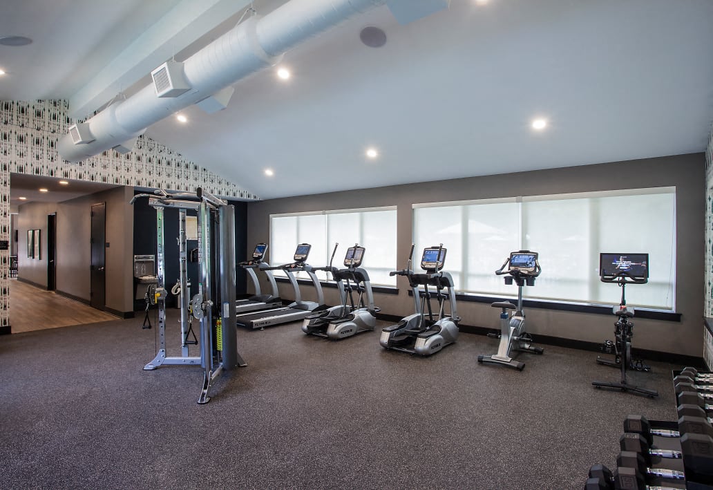 a gym with cardio equipment on the floor and windows