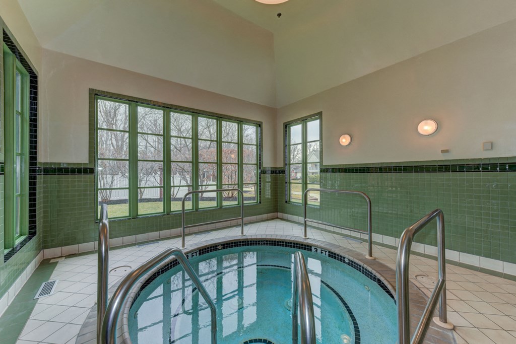an indoor swimming pool with green tiles and large windows