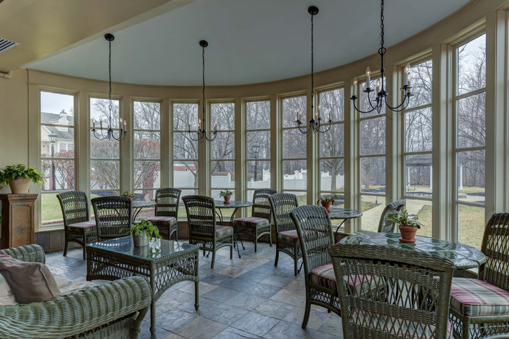 a sun room with tables and chairs and windows