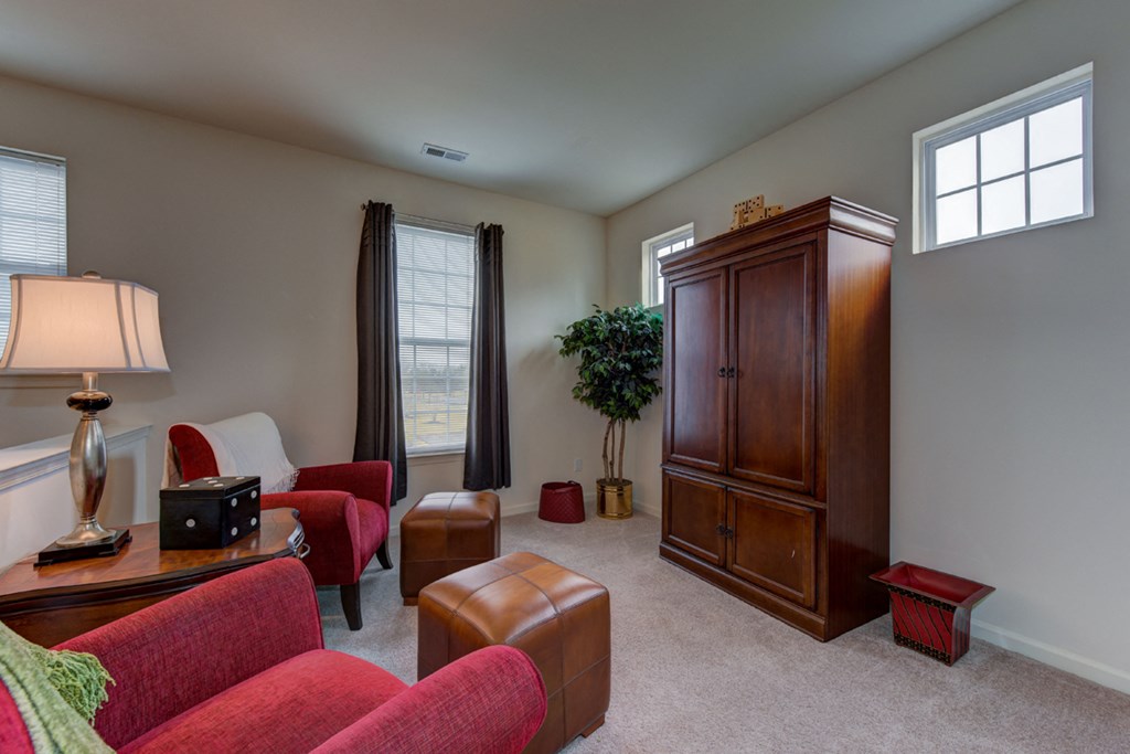 a living room with red furniture and a wooden armoire