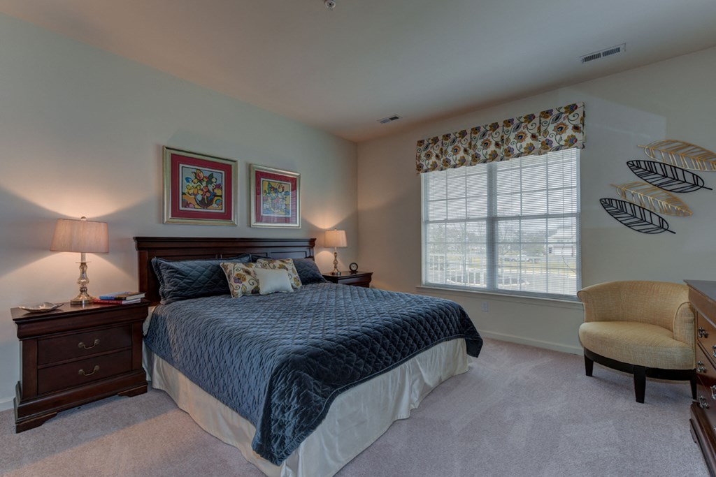 a bedroom with a bed and a chair and a window