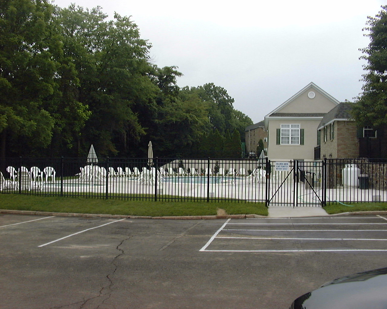 a white fence in front of a house with a parking lot