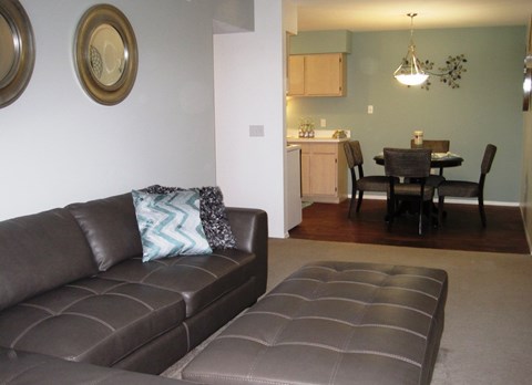 A brown couch with a blue and white pillow sits in a living room.