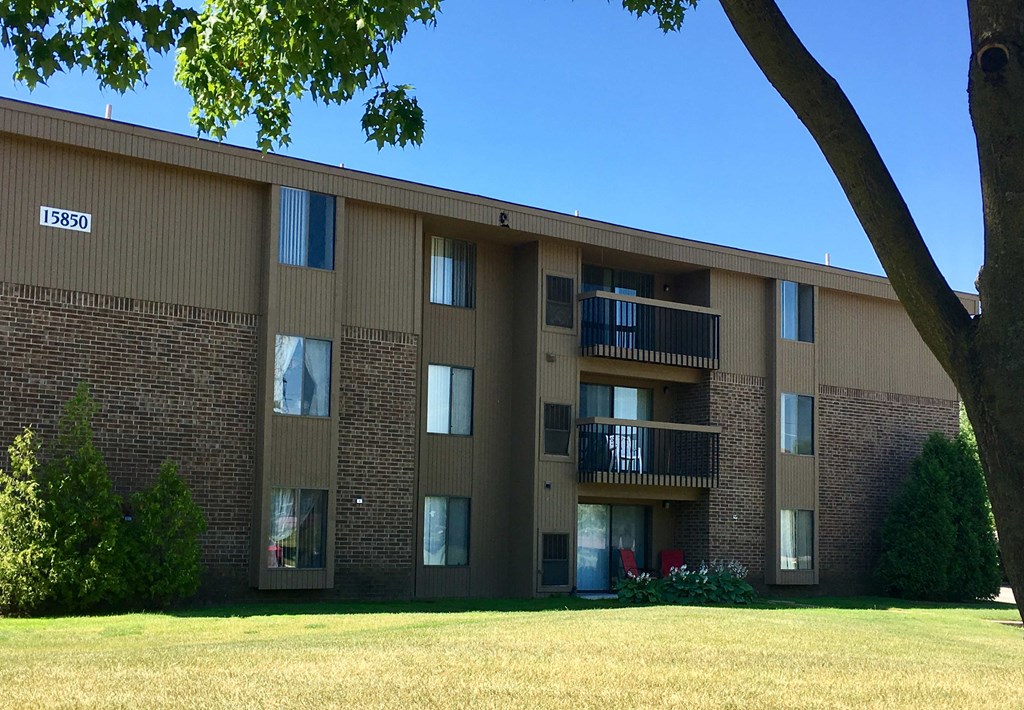 a brick apartment building with a lawn and a tree