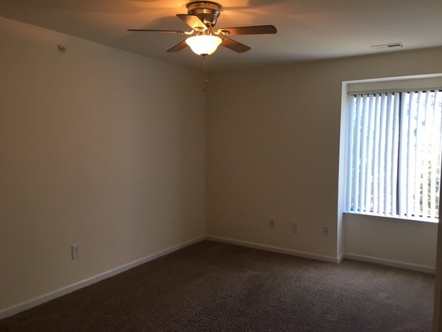 an empty living room with a ceiling fan and a window