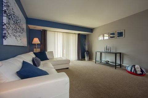 A living room with a white couch and a blue accent wall.