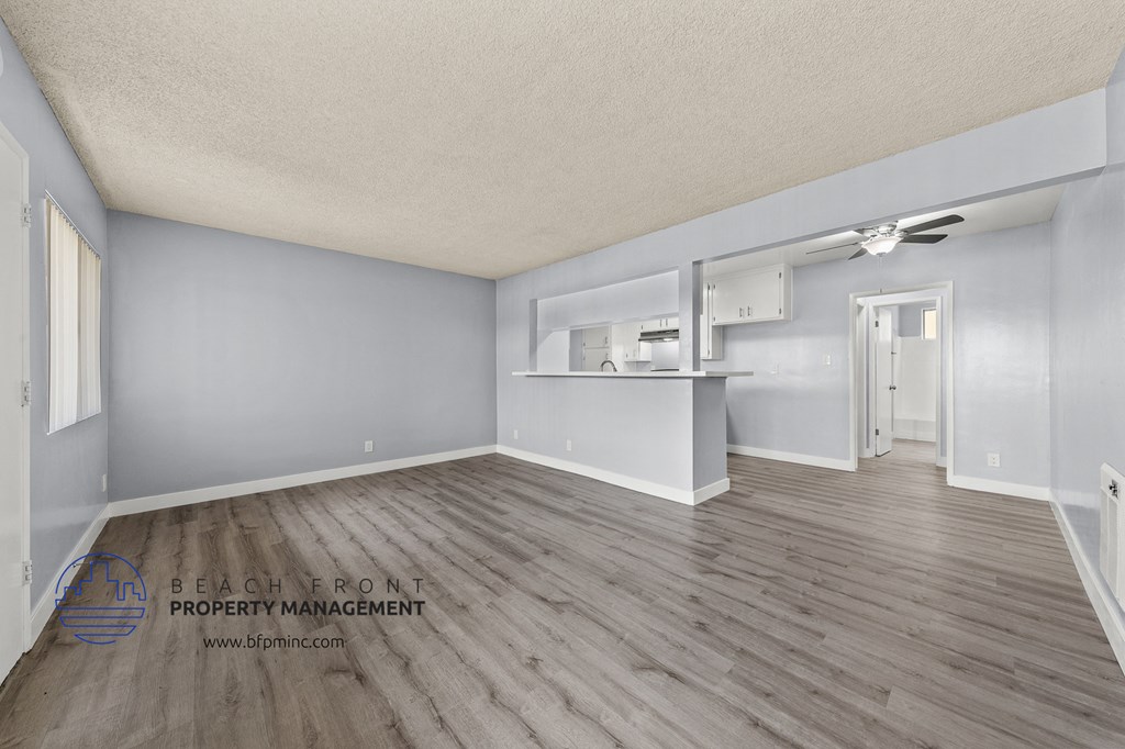 the living room and kitchen of an apartment with wood flooring