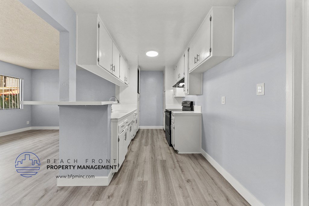 an open kitchen with white cabinets and white appliances and a wood floor