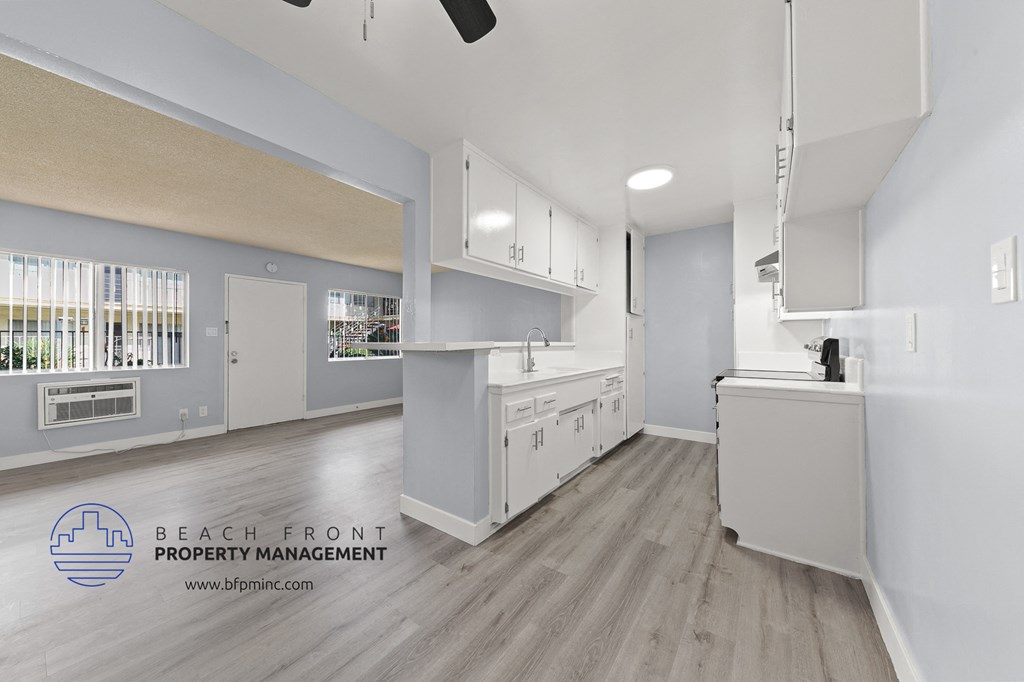 an open kitchen with white cabinets and white appliances and a wood floor