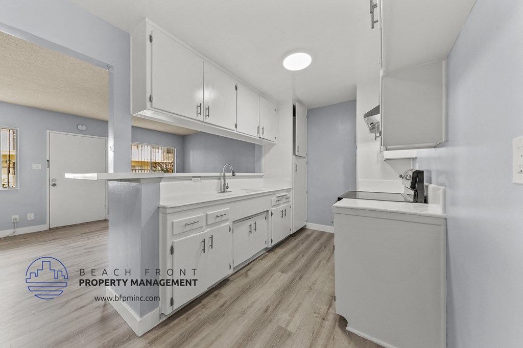 a white kitchen with white cabinets and white counter tops and a wooden floor