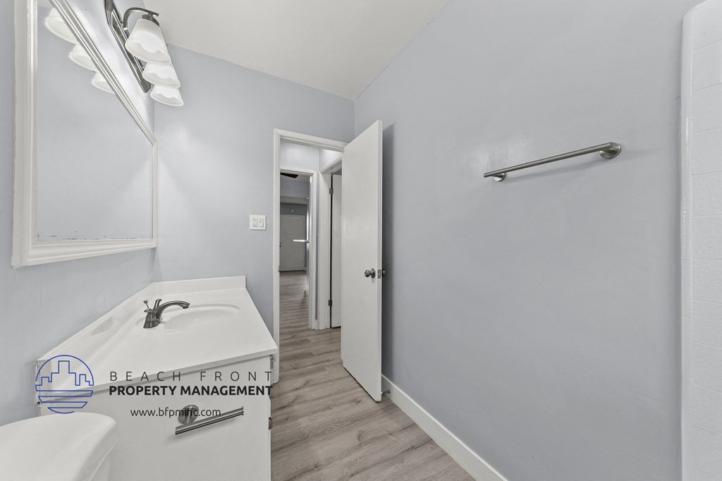 a bathroom with a sink and a mirror and a hallway to a closet