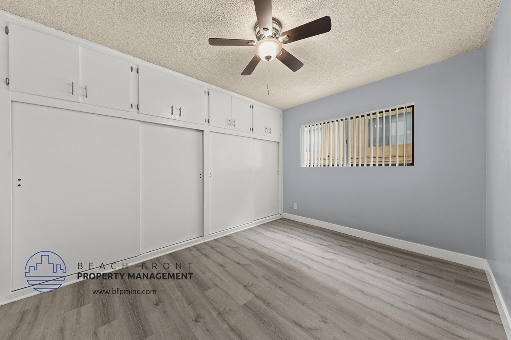 a bedroom with white cabinets and a ceiling fan