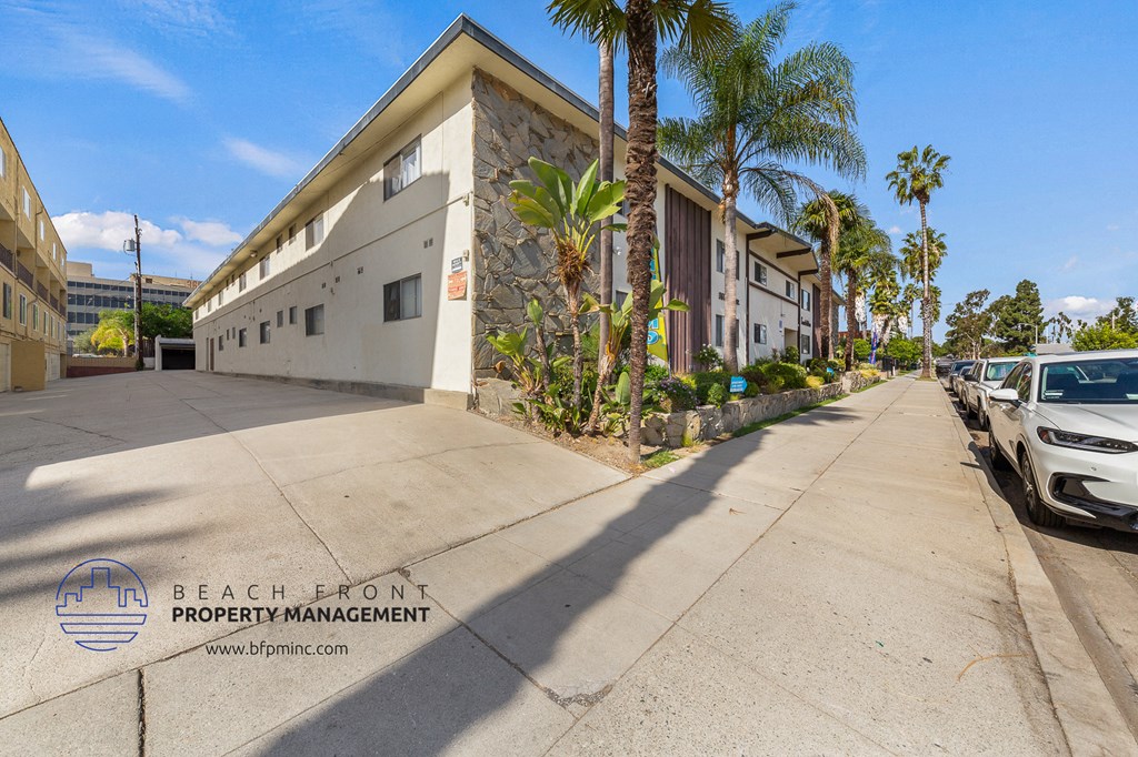 a large white building with palm trees and cars parked on a street