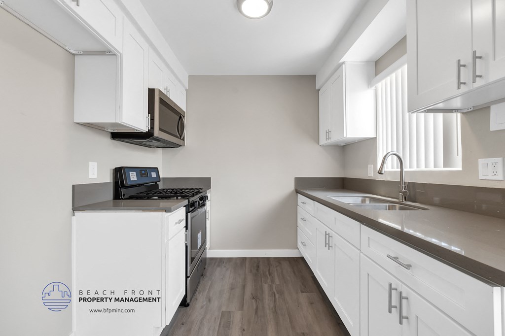 a kitchen with white cabinets and stainless steel counter tops and a stove and a microwave