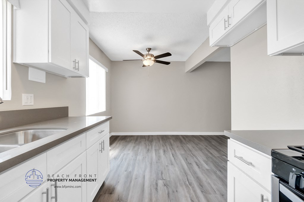 an empty kitchen with white cabinets and a ceiling fan