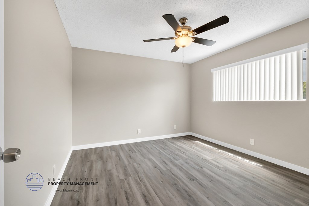 the spacious living room with hardwood floors and a ceiling fan
