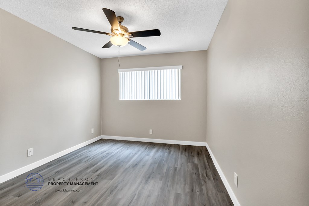 the spacious living room with hardwood floors and a ceiling fan
