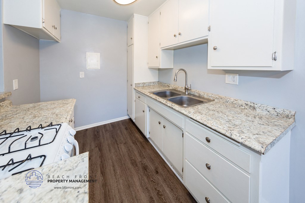 a kitchen with white cabinets and marble counter tops