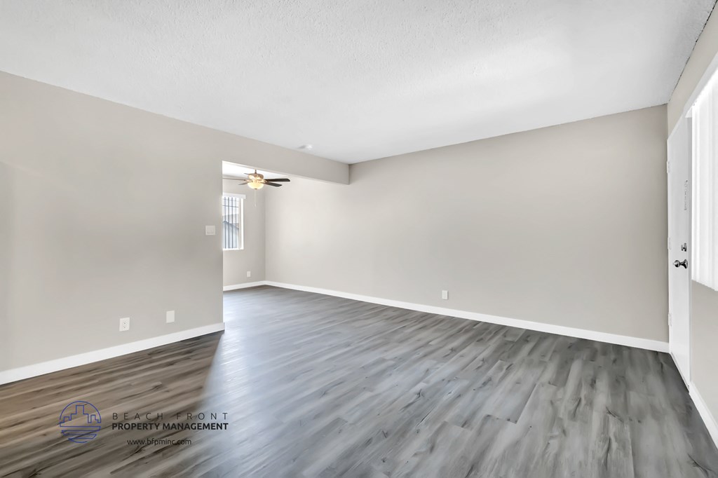 the spacious living room with hardwood flooring and white walls