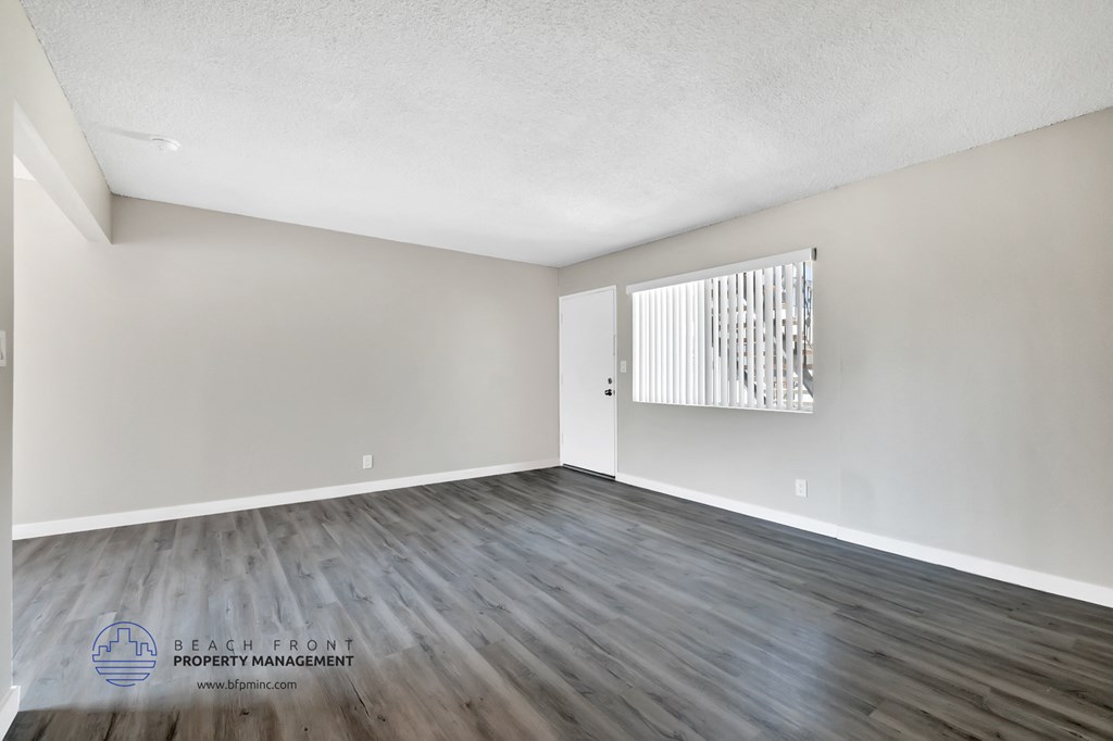 the living room of a new home with wood flooring and a window