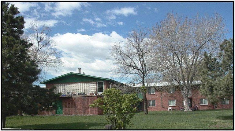 a red brick house with a green roof and a lawn