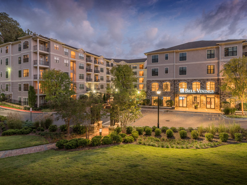 an exterior view of an apartment building at night with a lawn