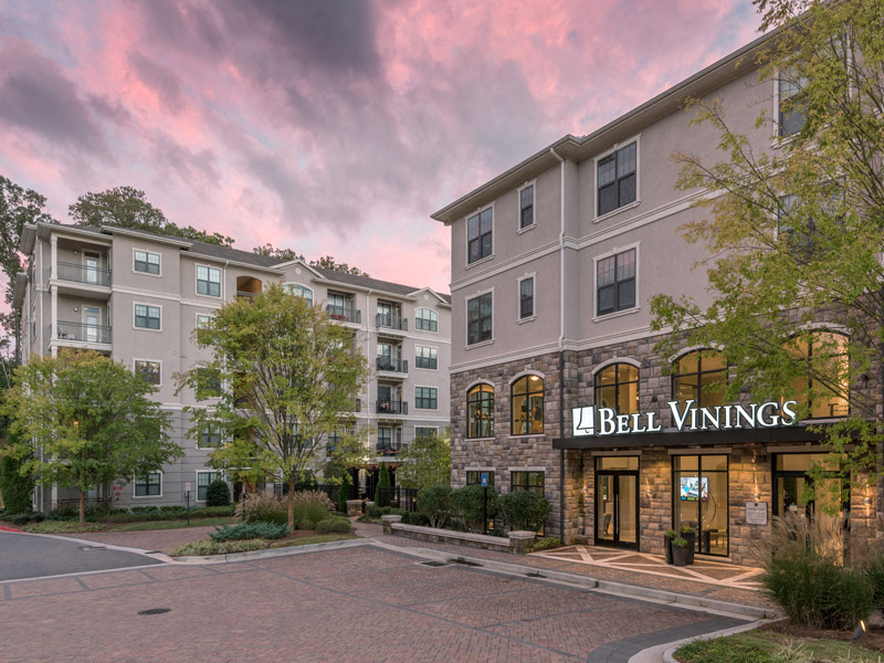 an exterior view of a building at dusk with trees and a parking lot