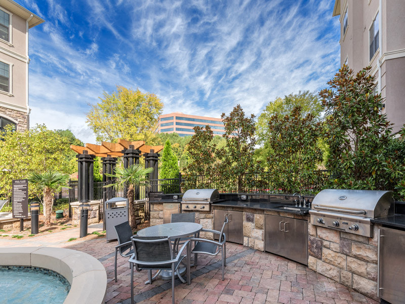 a patio with a barbecue grill and a table and chairs