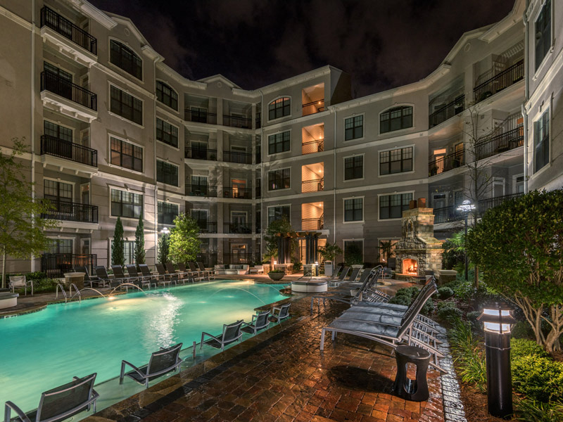 a swimming pool in front of an apartment building at night