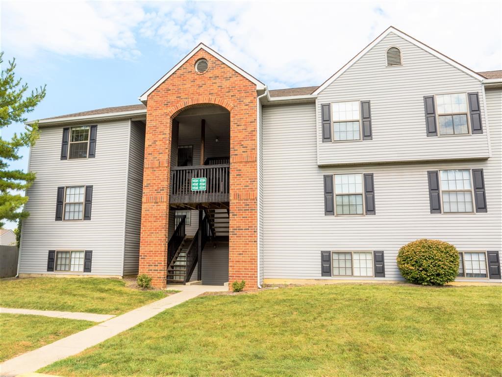the front of an apartment building with a lawn and a staircase