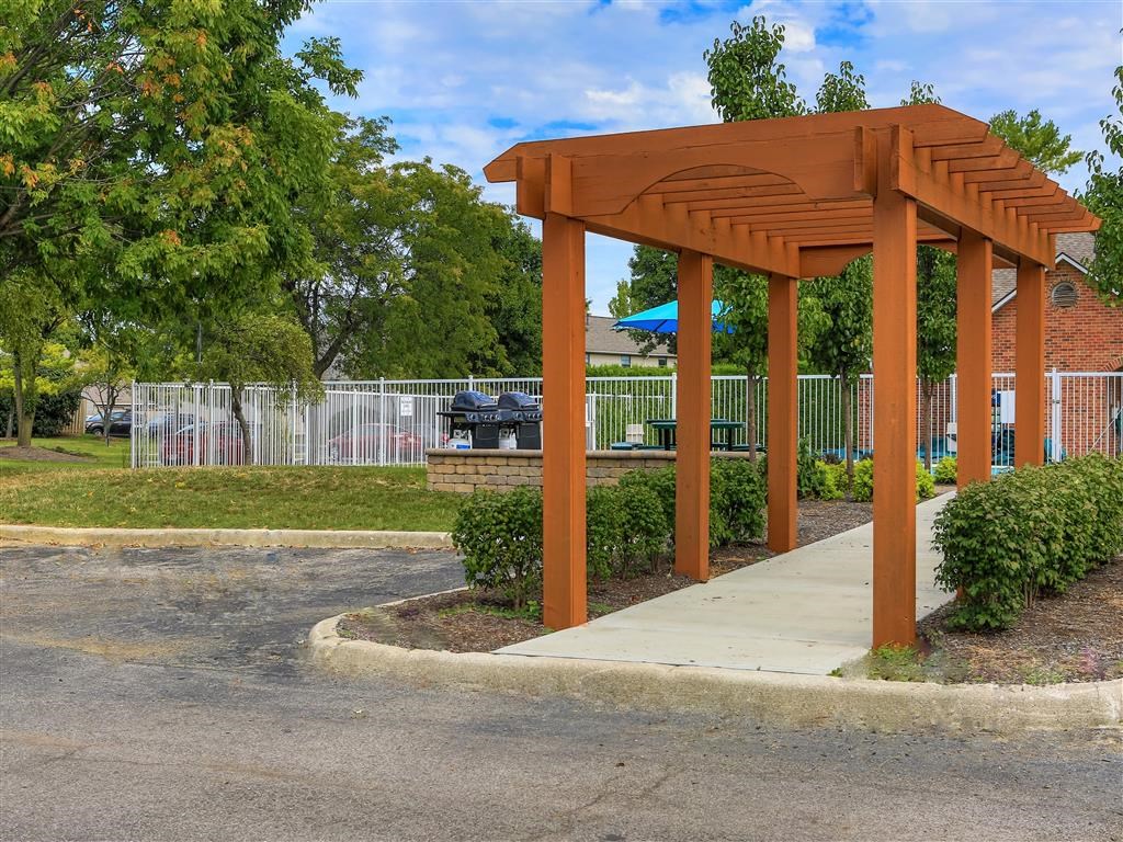 a wooden pavilion on a sidewalk in a park