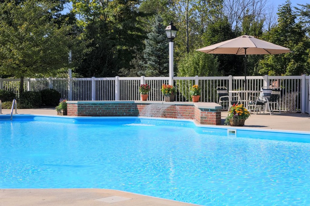 a swimming pool with an umbrella and a fence around it